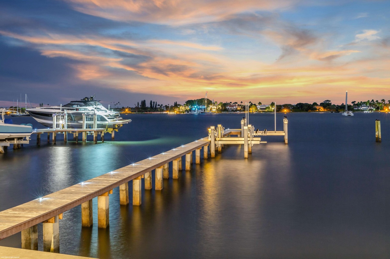 Aerial exterior view of the residence framed by the waterfront and surrounding palms.